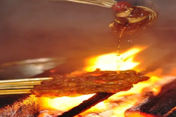 Brochettes de délicieux satay malaisien en cours de grillade